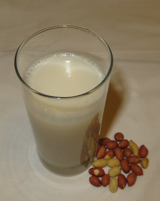 Glass of peanut milk and some peanuts